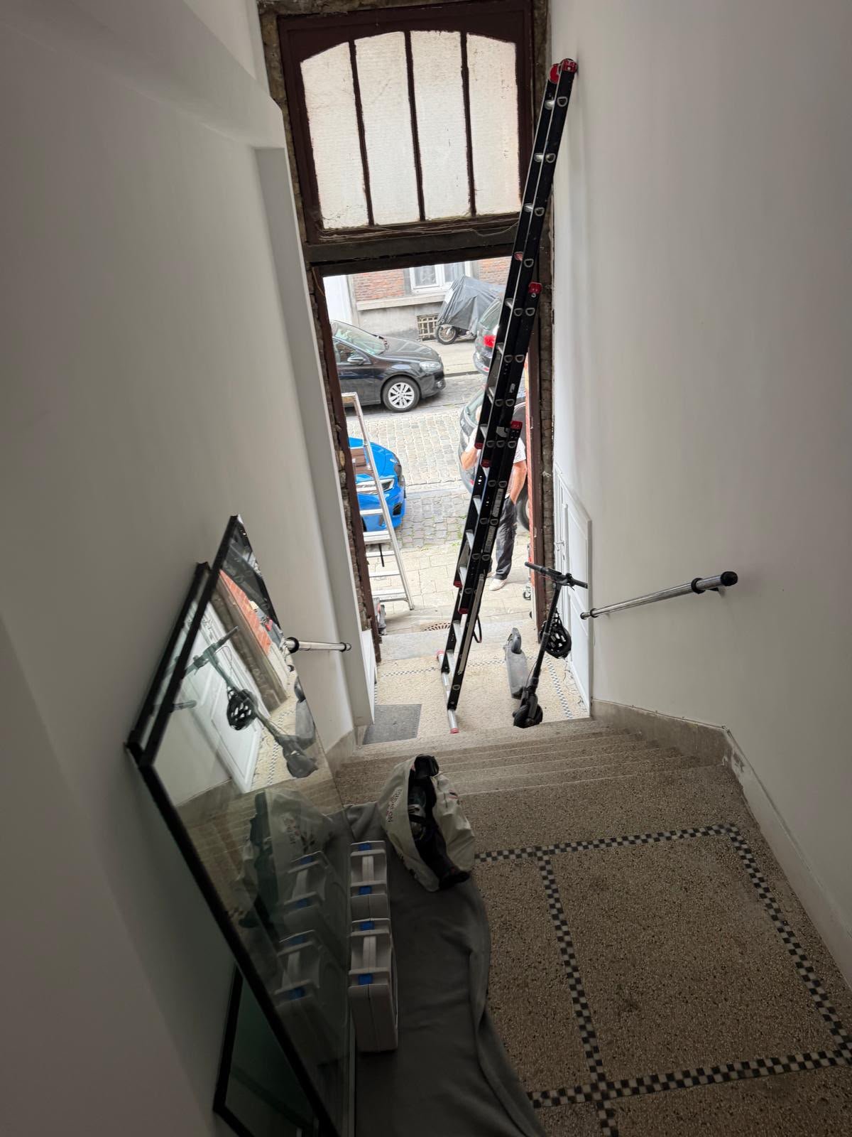 Hall d'entrée d'un immeuble avec échelle et imposte vitrée pendant des travaux de porte