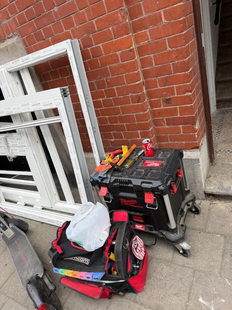 Caisse à outils et sacs de serrurier posés devant une façade en briques pendant une intervention