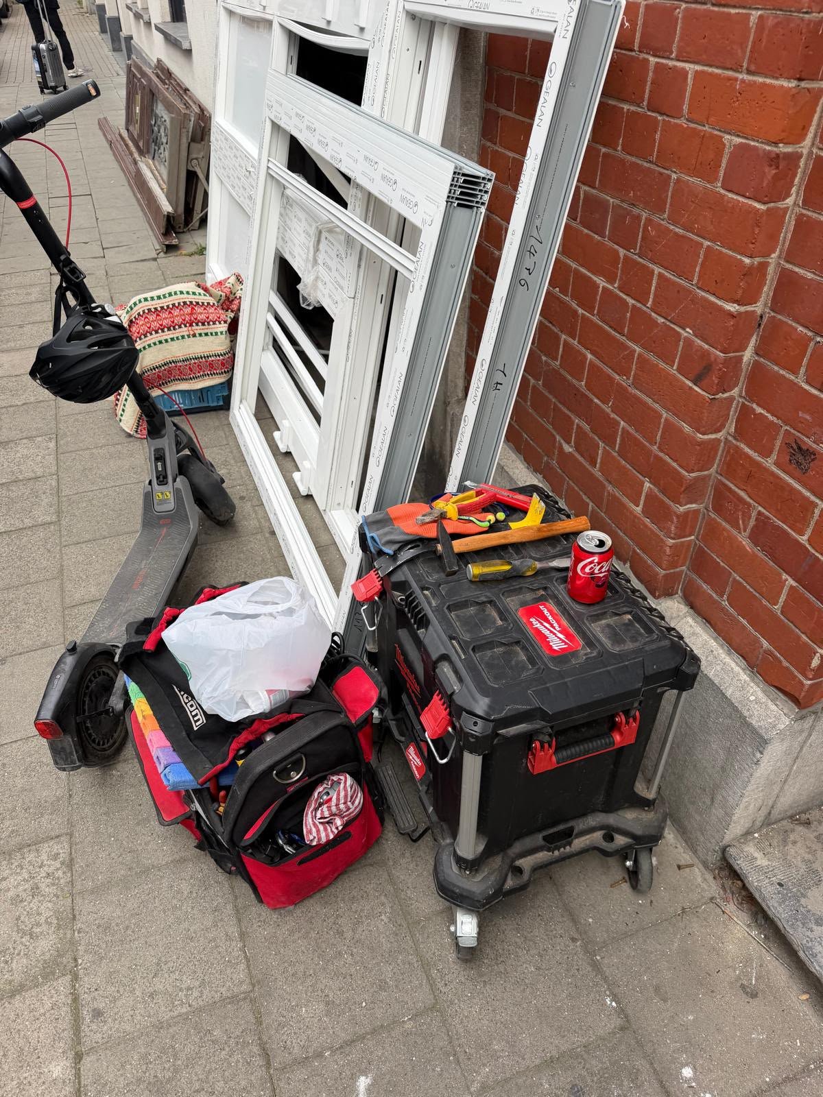 Outillage de serrurier et anciens châssis devant une façade en briques