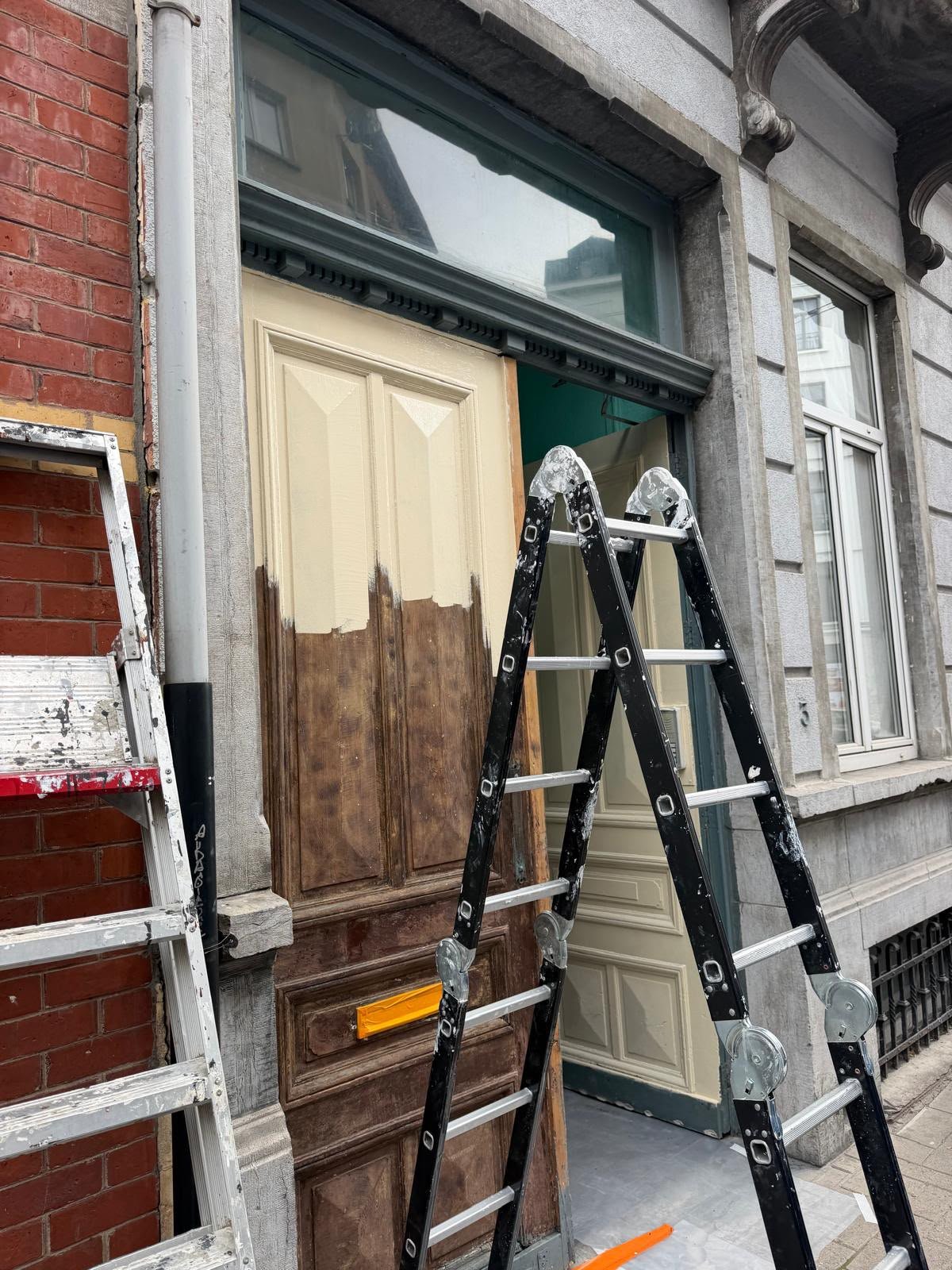 Rénovation d'une porte d'entrée en bois, échelle appuyée contre la façade